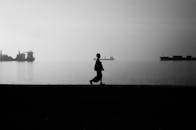 码头的剪影中，一个人正沿地平线上的船只行走