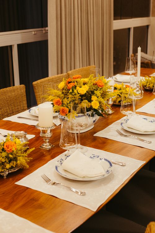 Free Beautifully set dining table adorned with yellow and orange floral arrangements, ready for an elegant dinner setting. Stock Photo