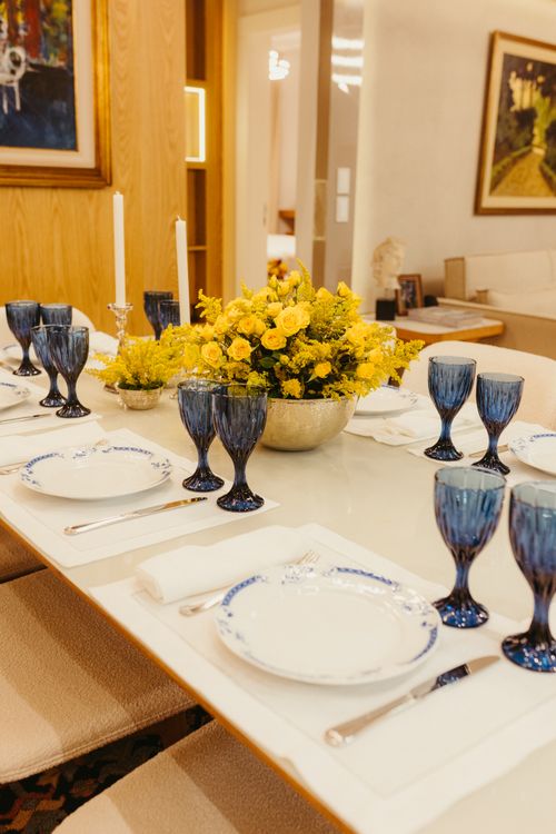 Free Beautifully set dining table with yellow flower centerpiece and blue glasses, creating an elegant and inviting atmosphere. Stock Photo