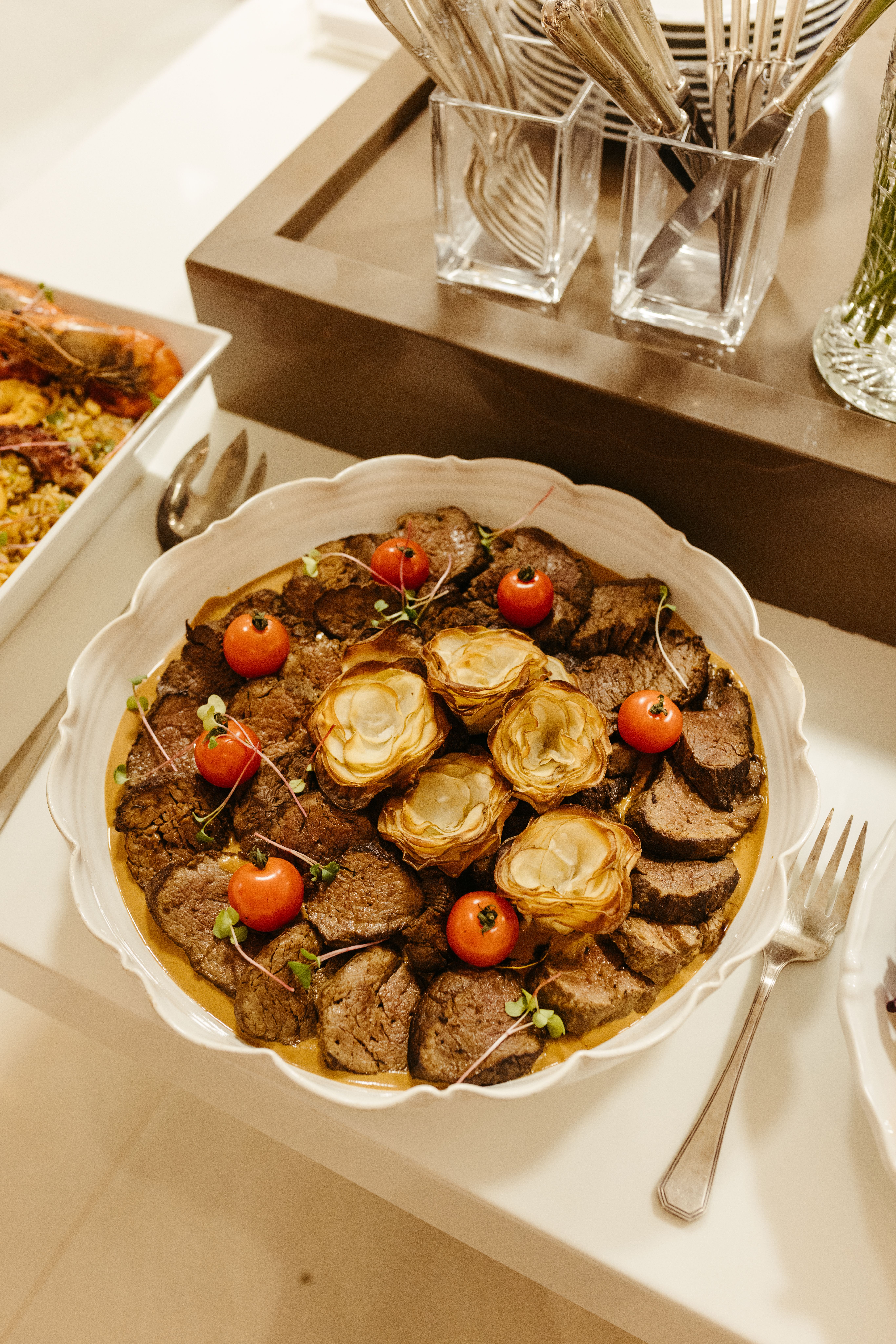 A thick roasted center-cut beef tenderloin sliced into rounds, showing a deep brown crust and evenly pink interior, plated with pan sauce.