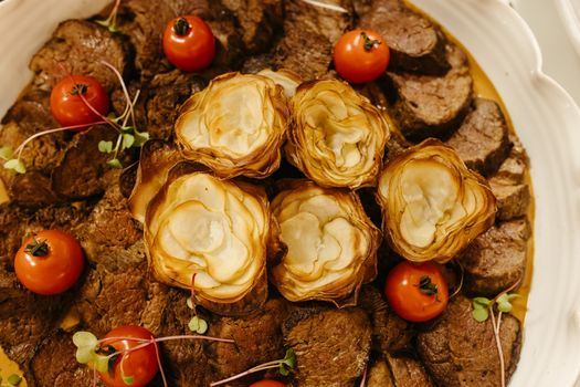 A delectable gourmet dish featuring roasted meats, crispy potatoes, and fresh cherry tomatoes.