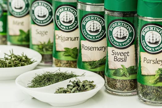 Assorted dried herbs in branded spice jars with bowls of loose herbs in the foreground.