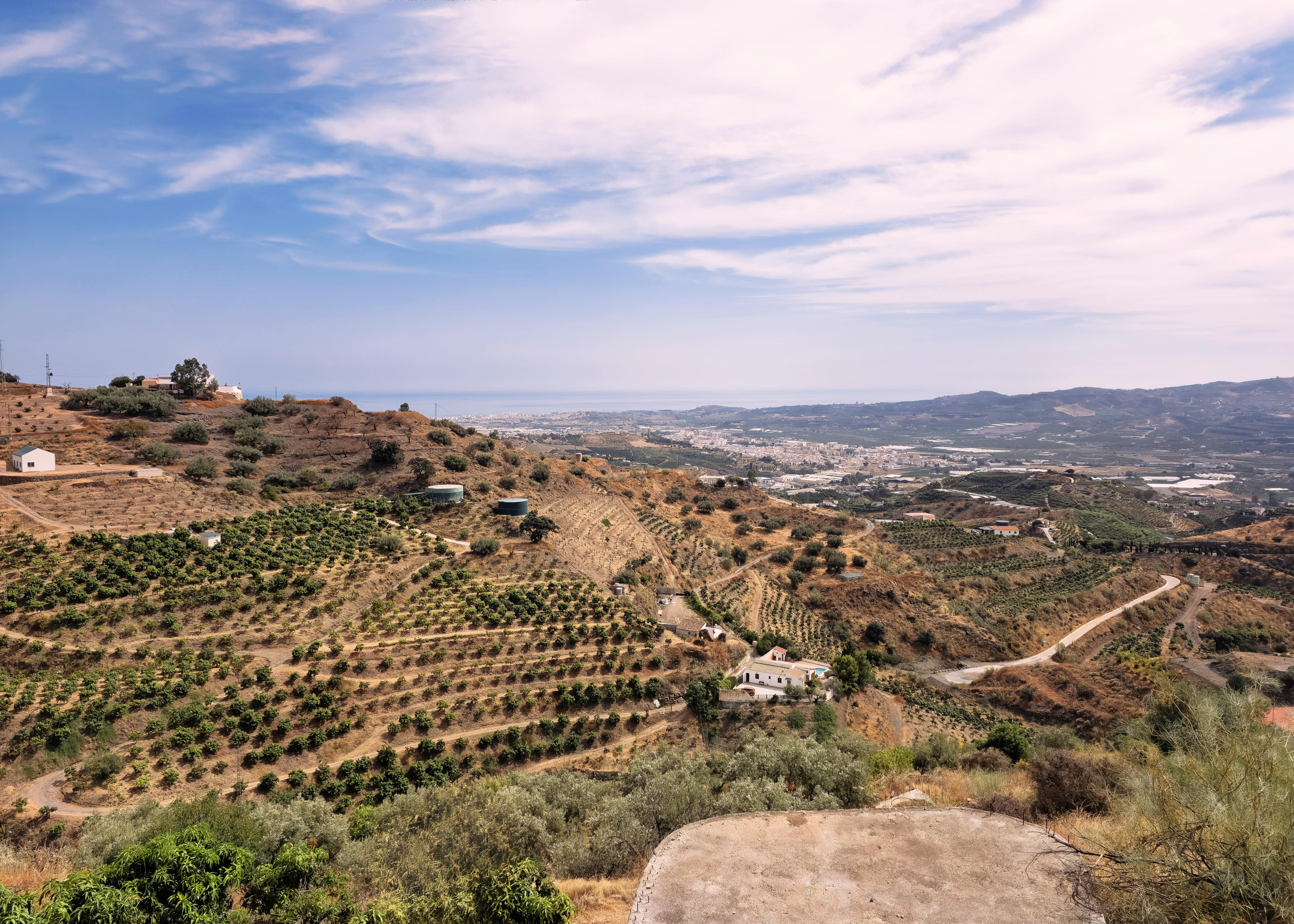 Scenic landscape of Vélez-Málaga with hills and farmland under a clear sky.