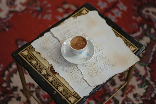 A delicate coffee cup on handwritten letters atop an ornate table with a vintage style, evoking a classic and artistic mood.