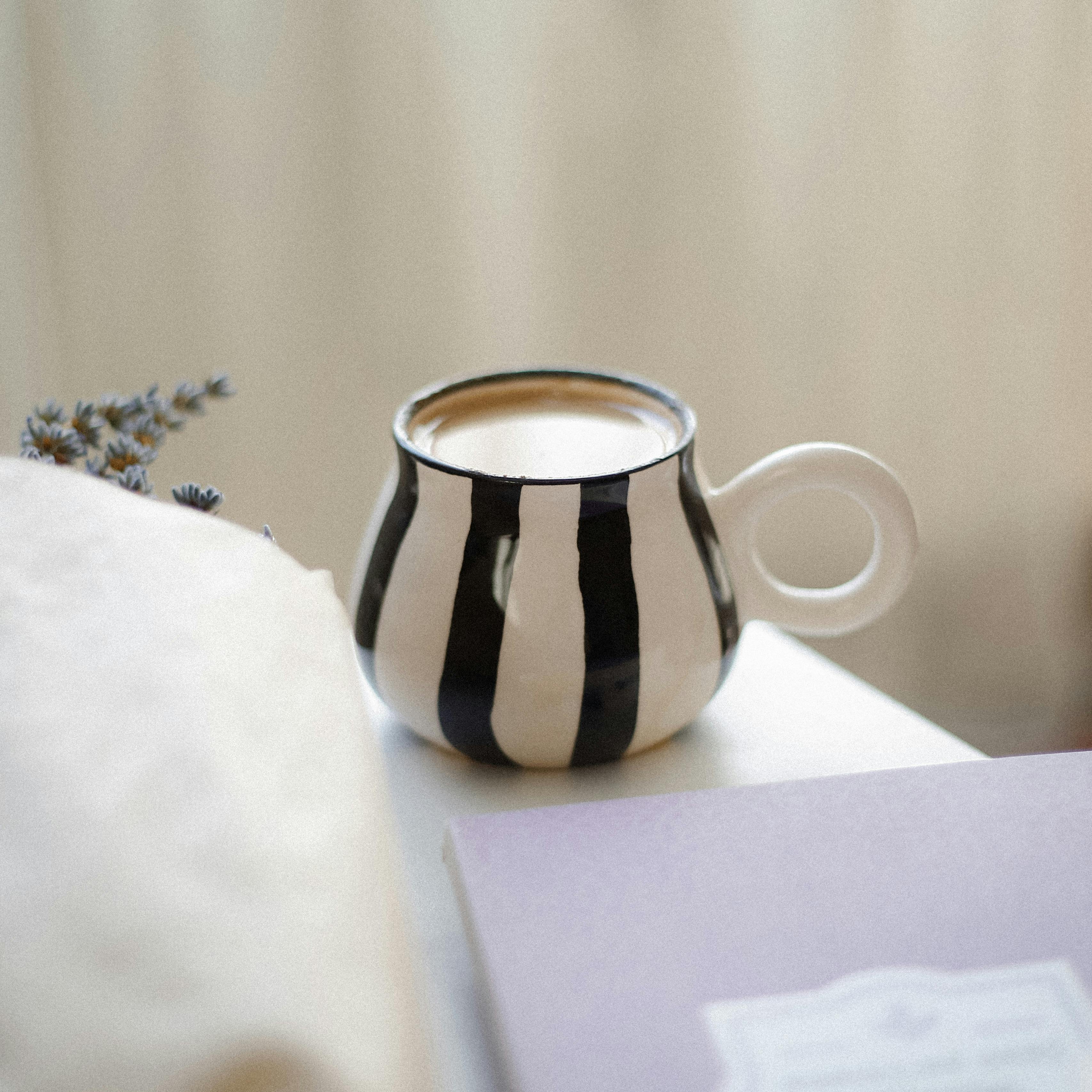 Aesthetic black and white striped ceramic mug filled with tea, beside a lavender sprig.