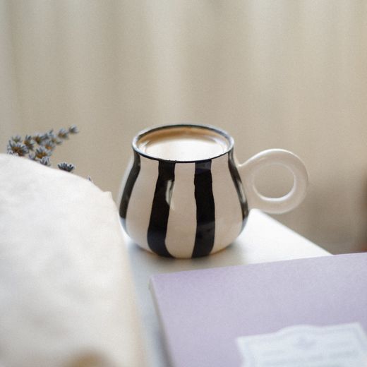 Striped ceramic mug filled with tea — photo by betul nur akyurek on Pexels