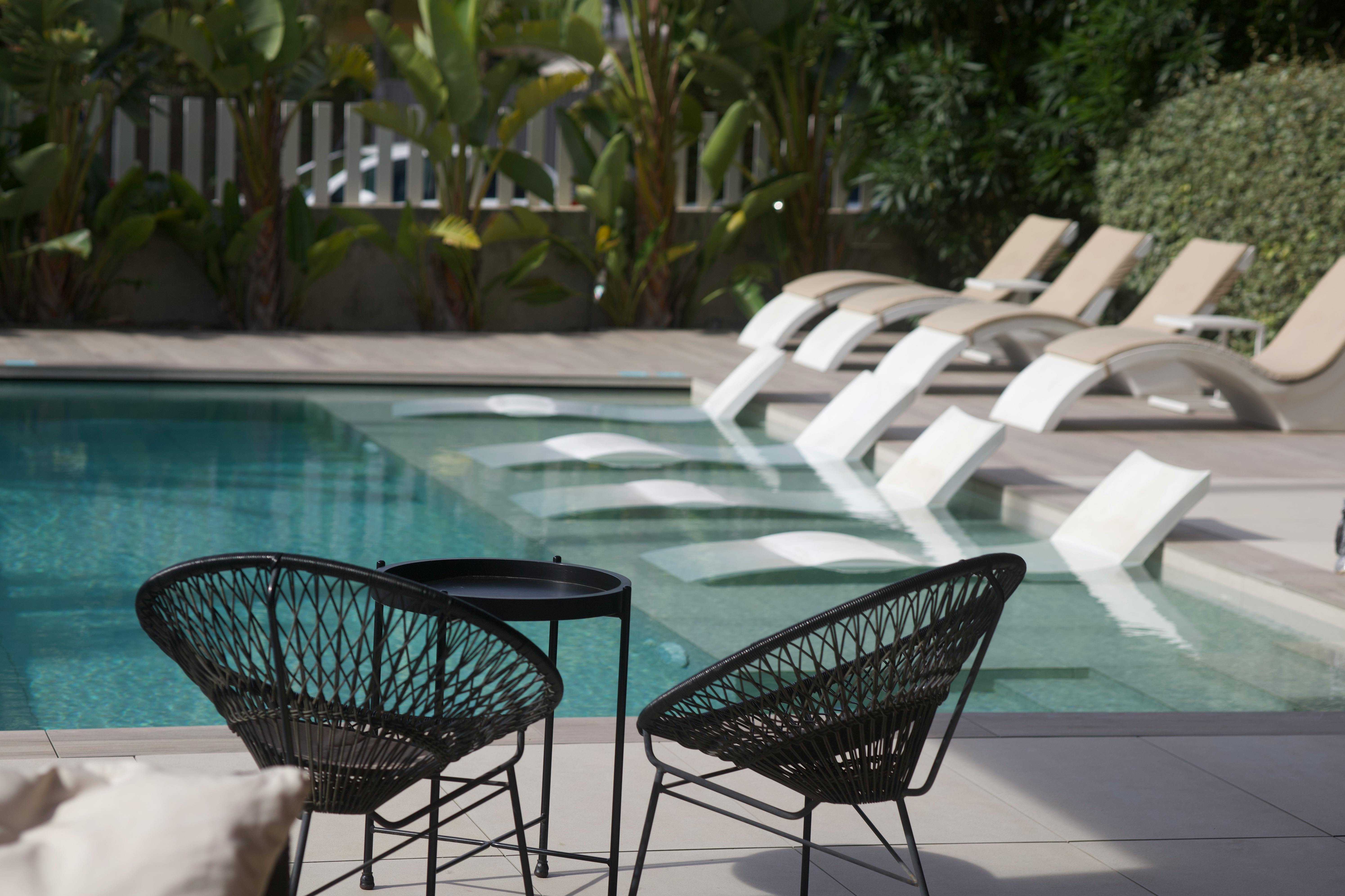 Relaxing outdoor pool area with modern chairs and lounge seats on a sunny day.