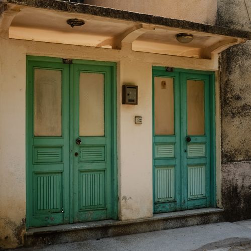 Free A pair of vintage teal doors in a rustic urban setting with old plaster walls. Stock Photo