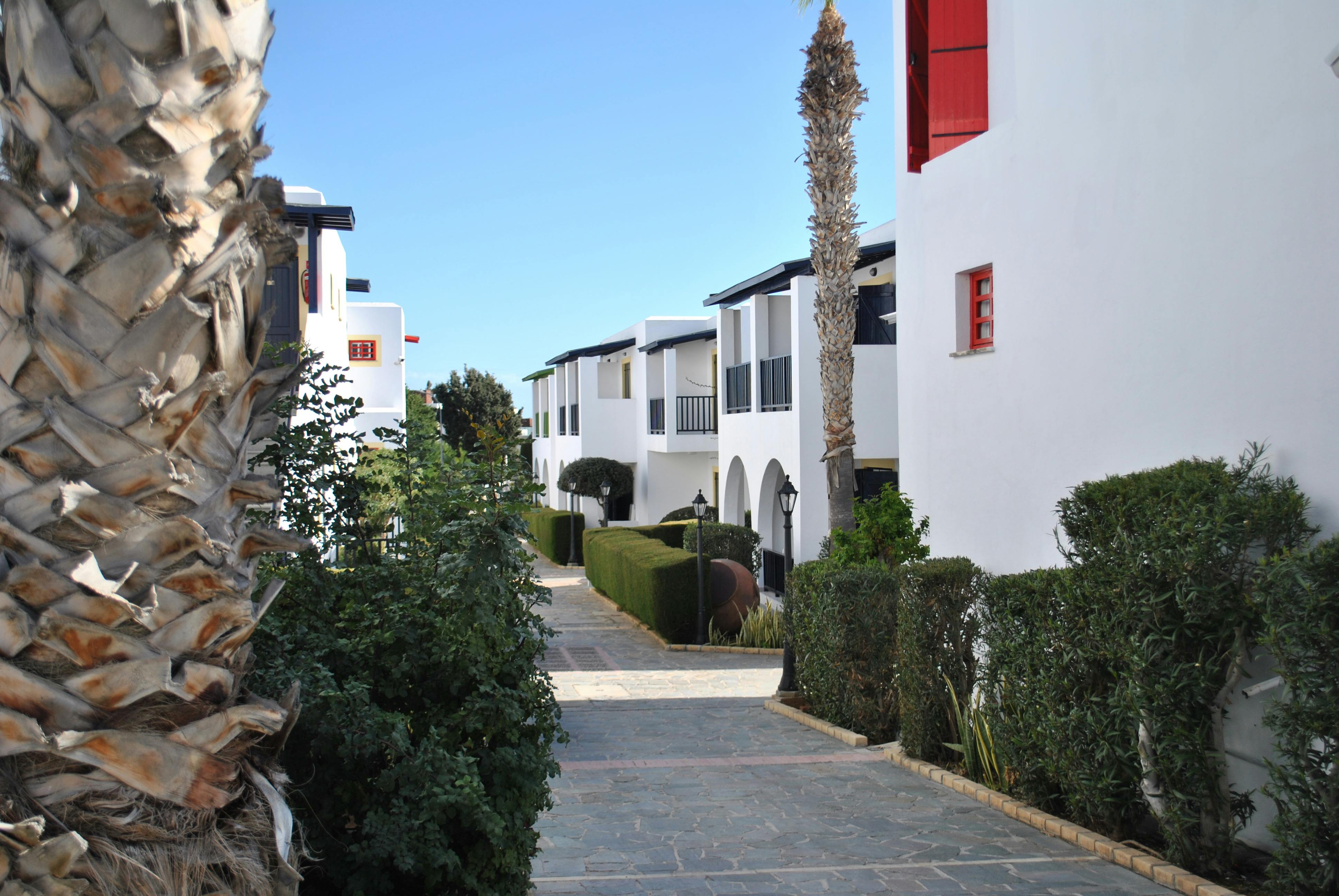 Scenic view of a Mediterranean-style residential pathway with white buildings and lush greenery.