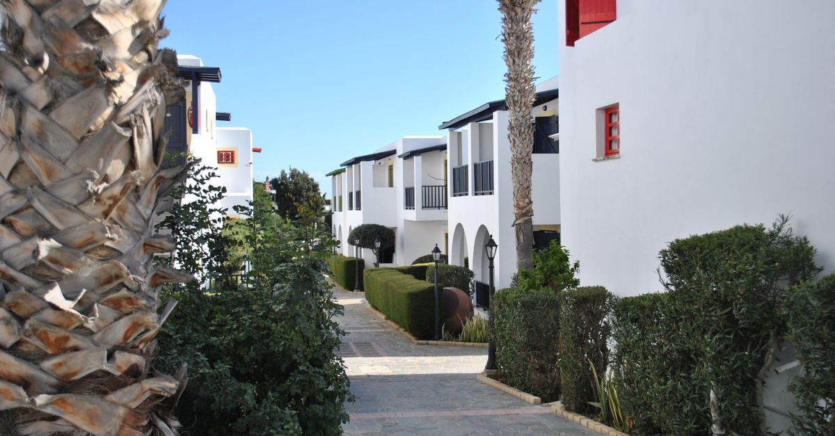 Scenic view of a Mediterranean-style residential pathway with white buildings and lush greenery.