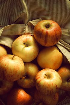 A warm, rustic still life of fresh apples arranged on striped fabric.