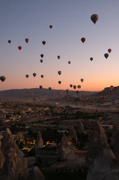 Stunning sunrise view of hot air balloons over Cappadocia's unique landscape in Türkiye.