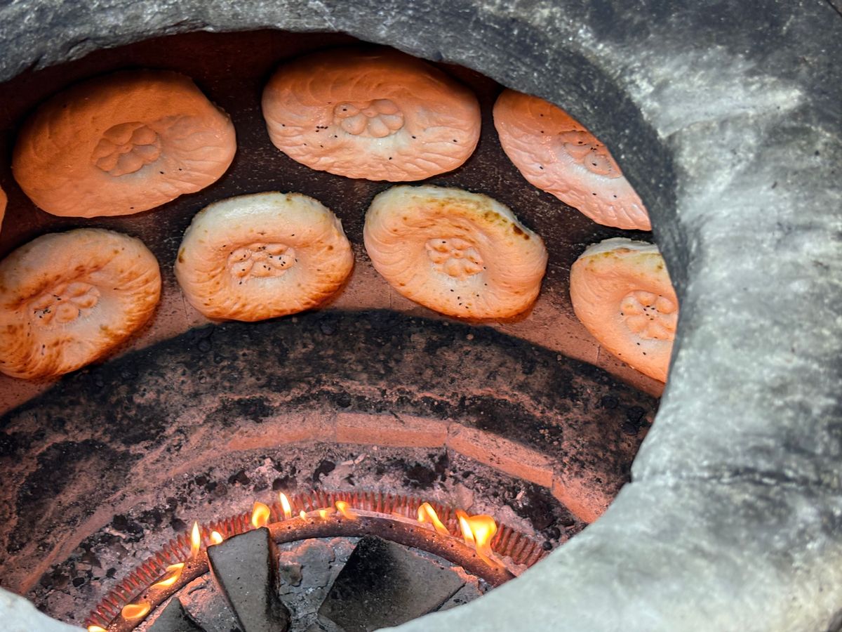Bread baking inside a ring of flame in a clay tandoor