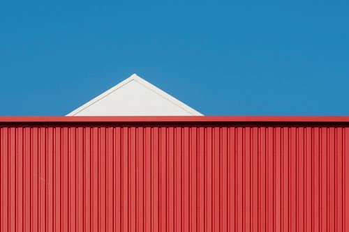 Free A minimalist photo of a red and white building against a clear blue sky. Stock Photo