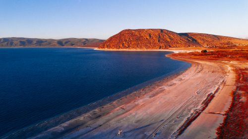 Free Breathtaking aerial view of a tranquil blue sea and vibrant coastal landscape at golden hour. Stock Photo