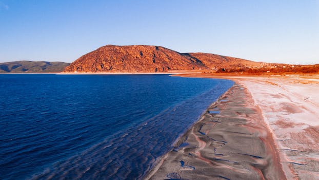 Aerial shot of Salda Lake's clear blue waters and mountain in golden hour light.