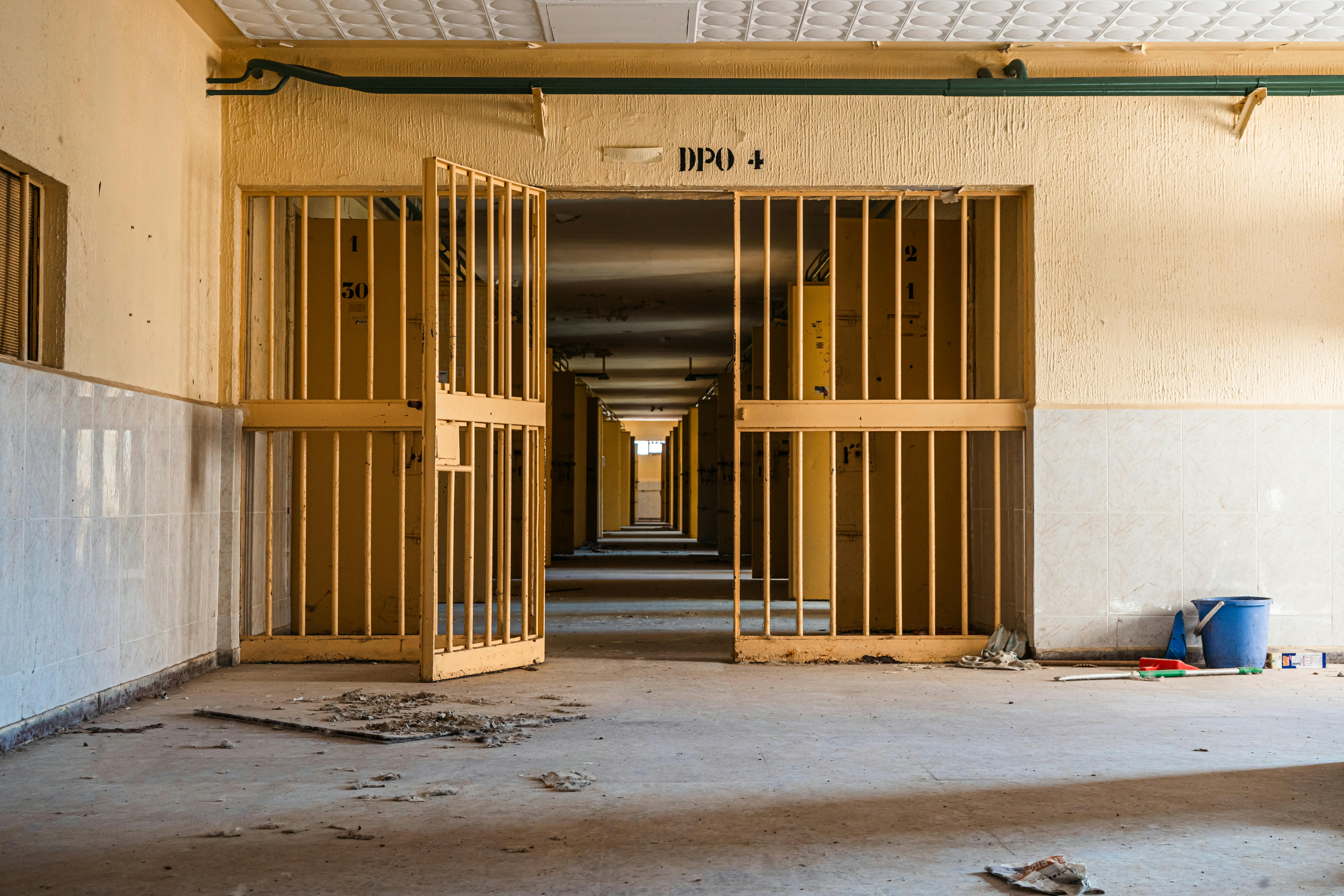 Interior view of an abandoned building featuring open gates and shown in a long corridor perspective.