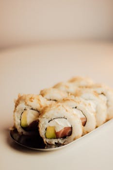 A close-up shot of sushi rolls with avocado and fish on a plate, ideal for culinary themes.
