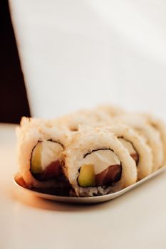Close-up of delicious sushi rolls with tuna and avocado on a plate.