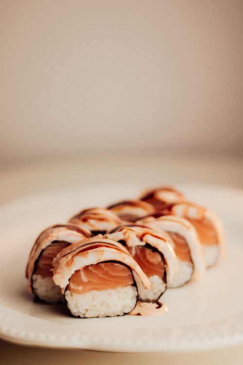Free Delicious sushi roll with fresh salmon and creamy sauce on a white plate. Stock Photo