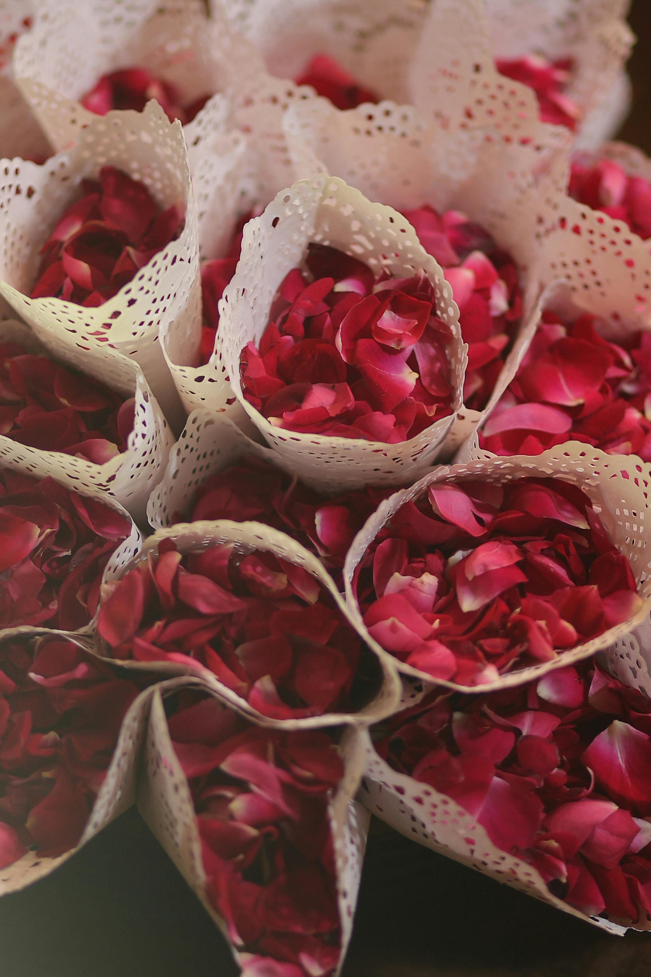 Beautifully arranged red rose petals wrapped in delicate lace paper cones.