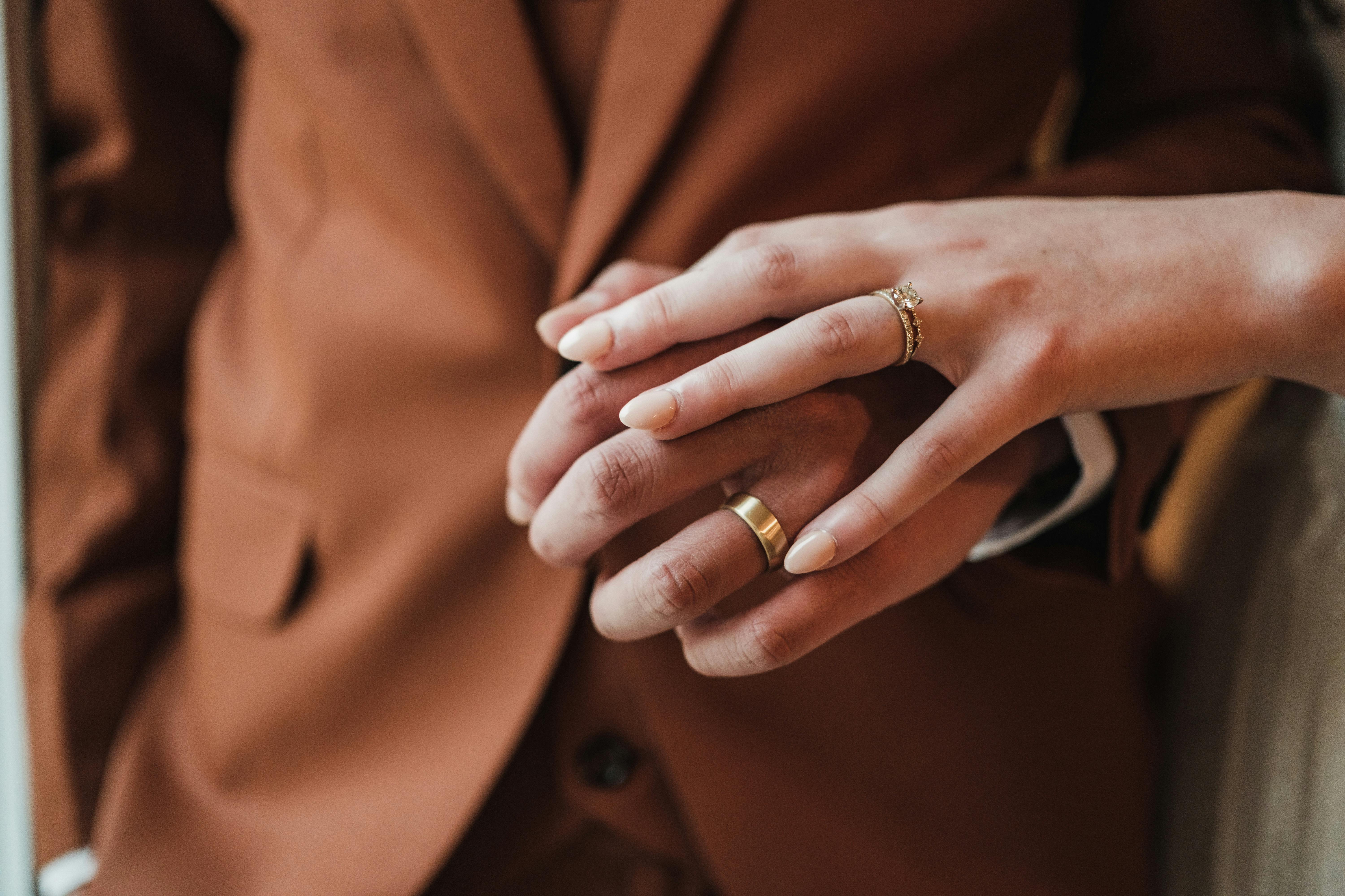 無料 愛と誓いを象徴する結婚指輪をはめたカップルの手の親密なクローズアップ。 写真素材