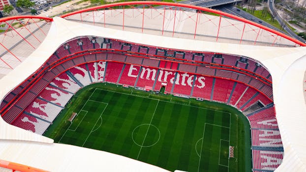 A stunning aerial shot of the iconic Estádio da Luz in Lisbon, showcasing its vibrant red seating and lush green field.