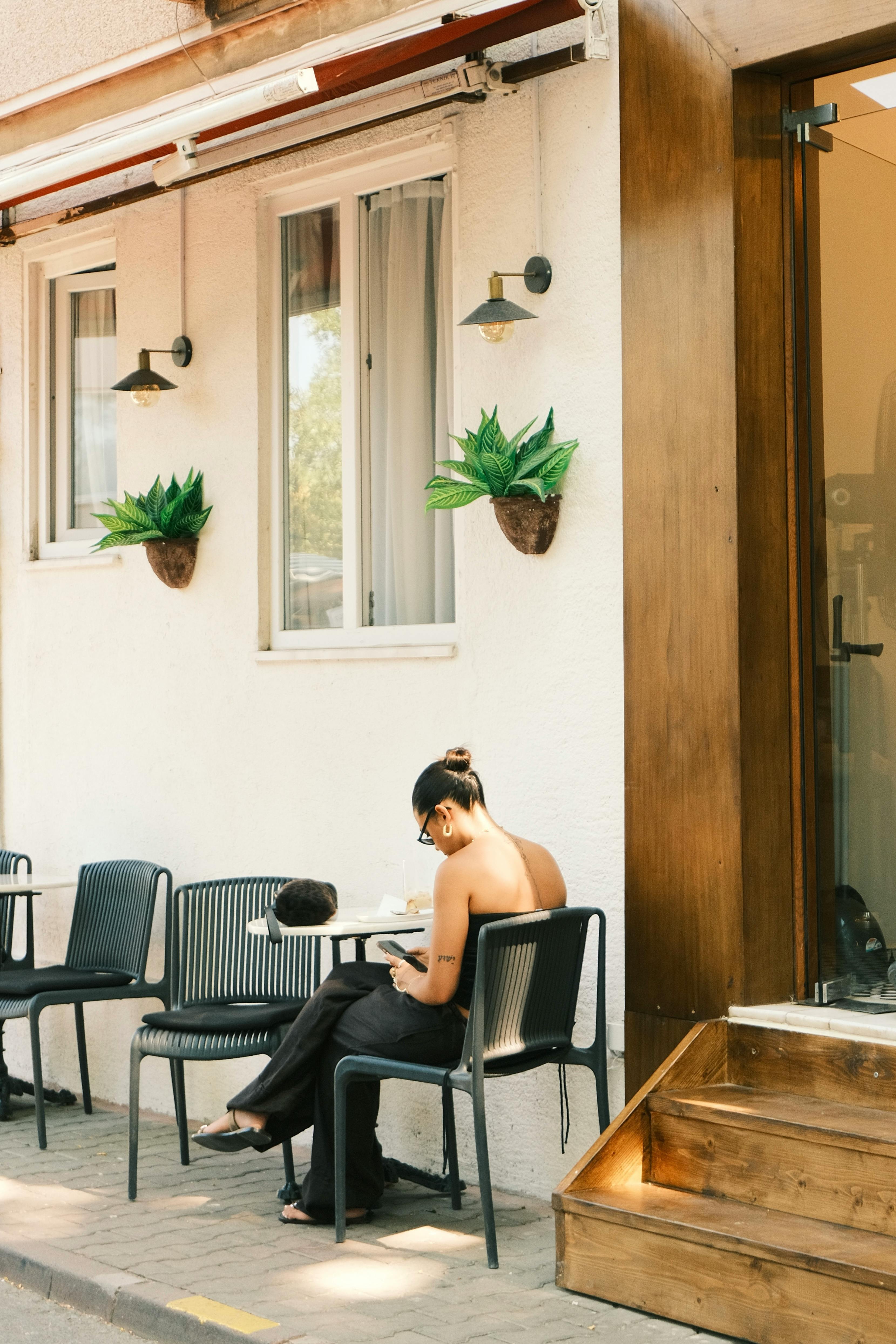 A woman reads at an outdoor cafe in Istanbul, enjoying a sunny summer day.