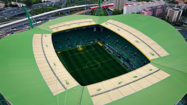 Stunning aerial view of Estádio José Alvalade in Lisbon, showcasing empty green football field and surrounding structures.