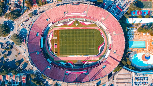 High-angle aerial shot of Morumbi Stadium in São Paulo, featuring the vibrant green field and red seating.