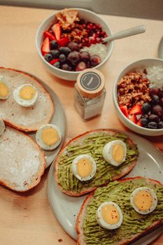 Top view of avocado toast and fruit bowls with eggs for a nutritious breakfast.
