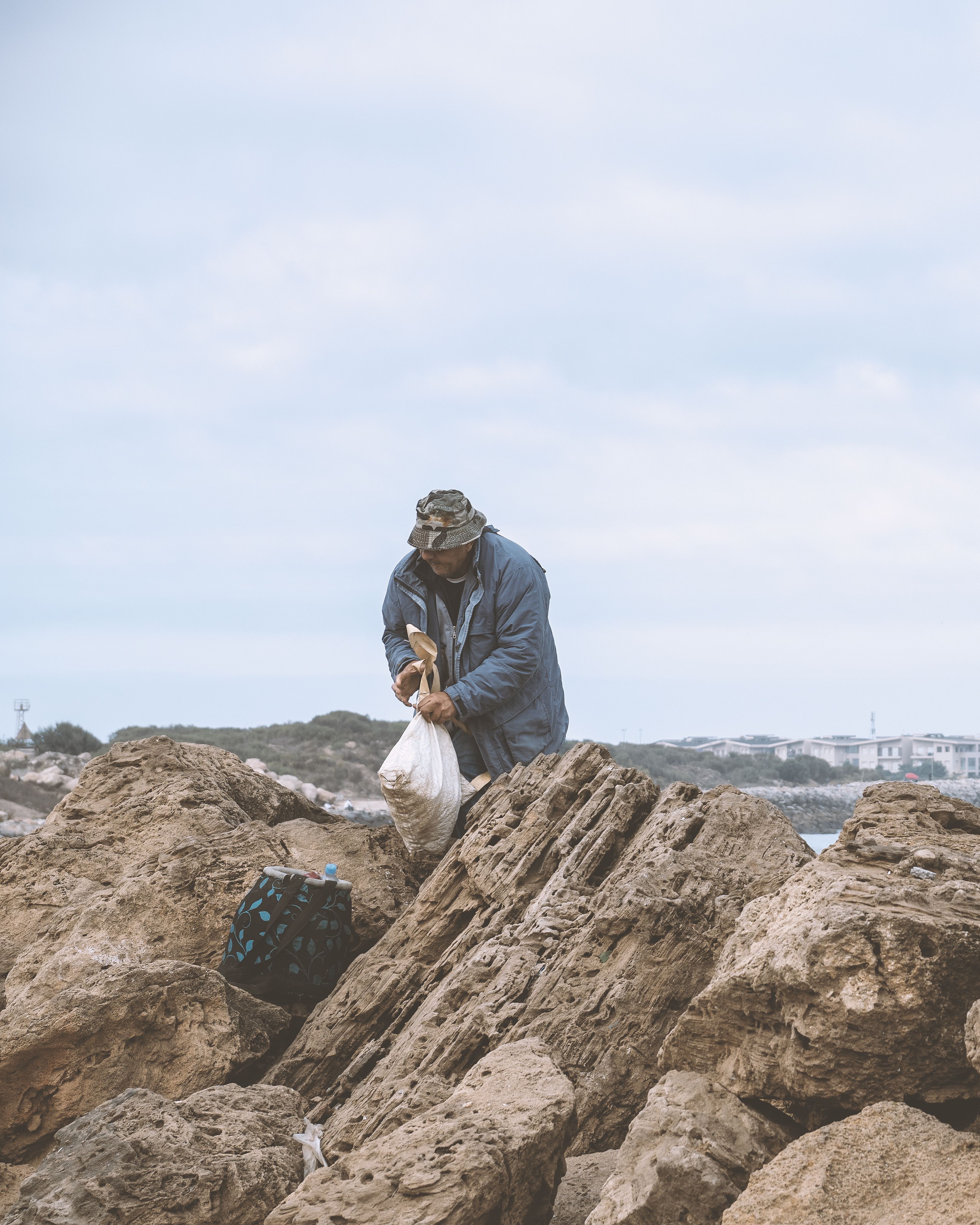 Man Foraging on Rocky Shoreline for Seafood · Free Stock Photo