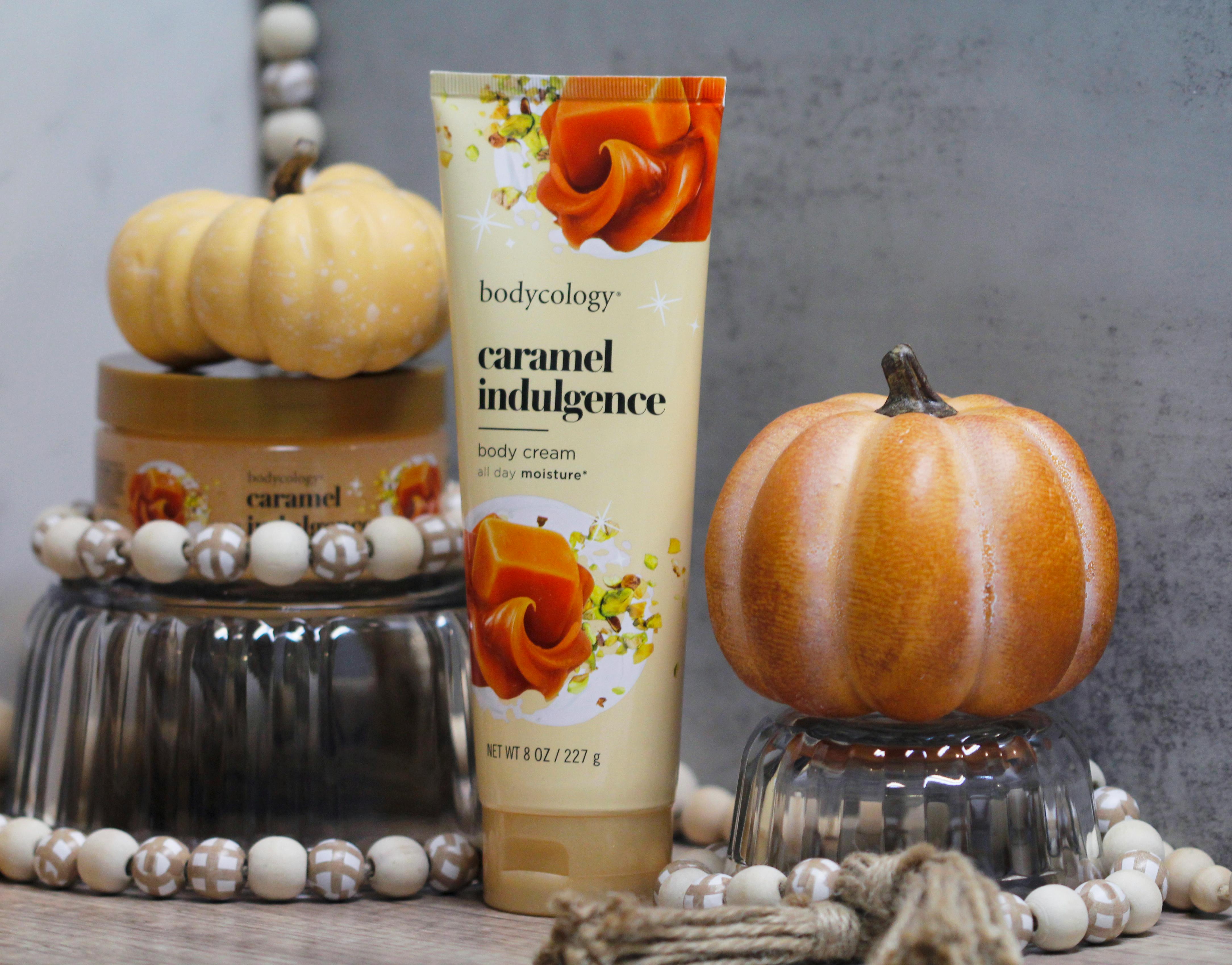 Bodycology Caramel Indulgence body cream with autumn decor featuring small pumpkins.
