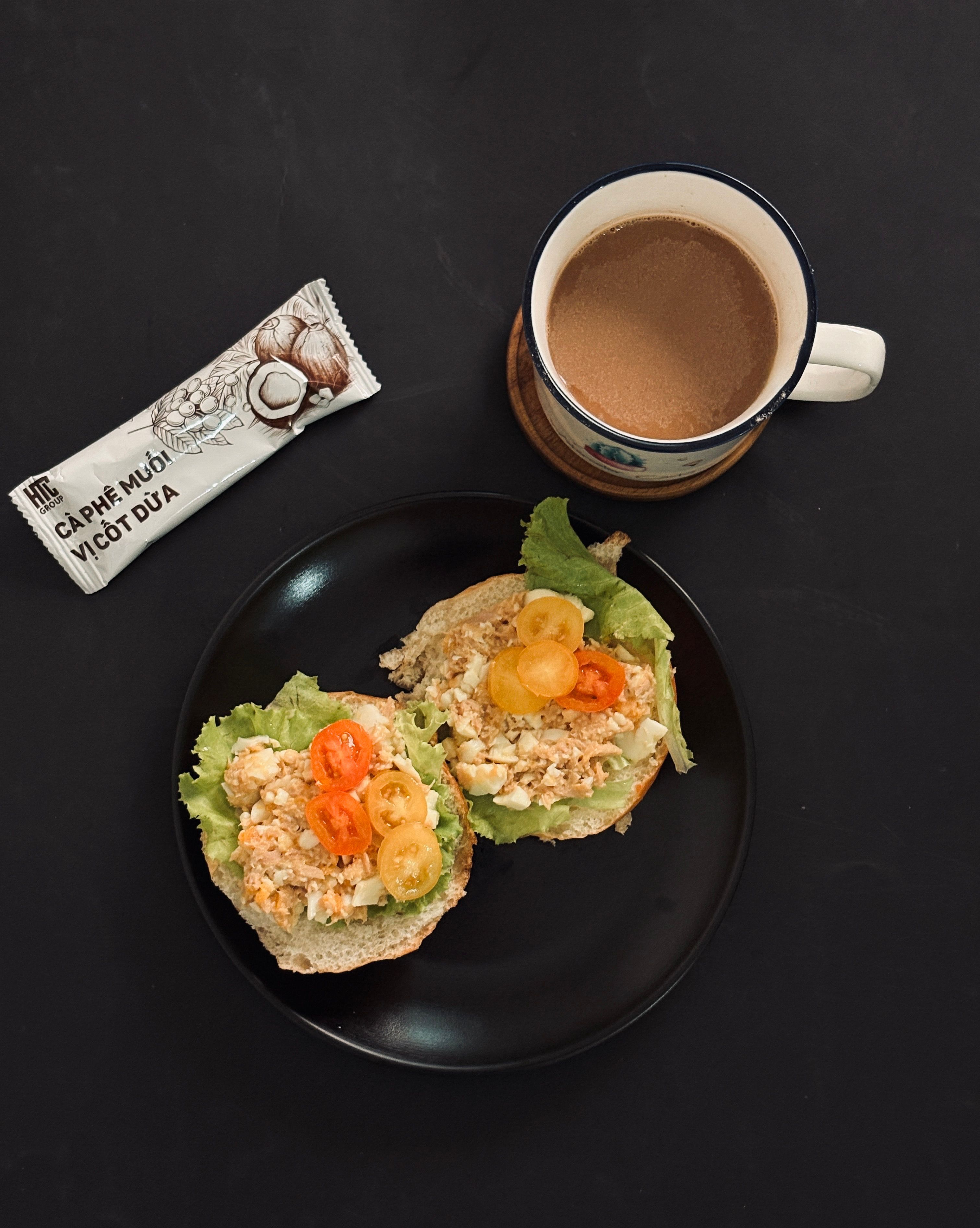 Top view of a delectable breakfast spread featuring a fresh vegetable sandwich and a warm cup of coffee.