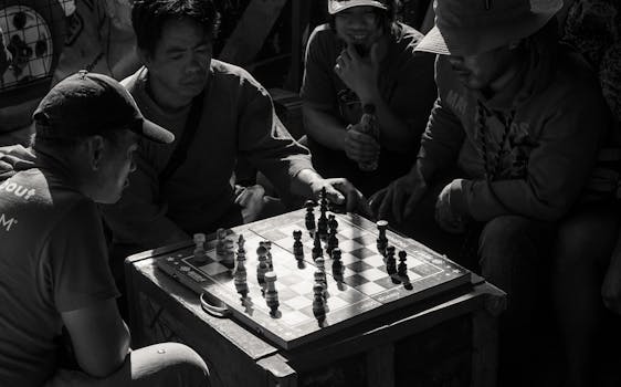 A group of men intensely focused on a street chess game in black and white.