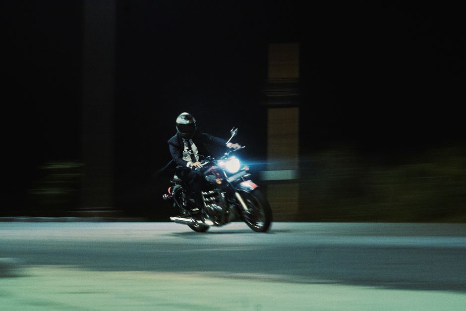 Dramatic shot of a motorcyclist speeding through the night, headlights illuminating the way.