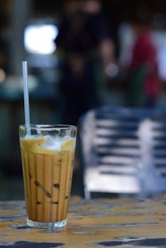 A refreshing glass of iced coffee with a straw, perfect for enjoying outdoors in warm weather.