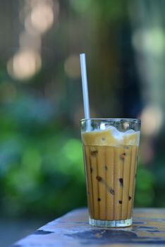 A tall glass of iced coffee with a straw, perfect for a summer day outdoors.