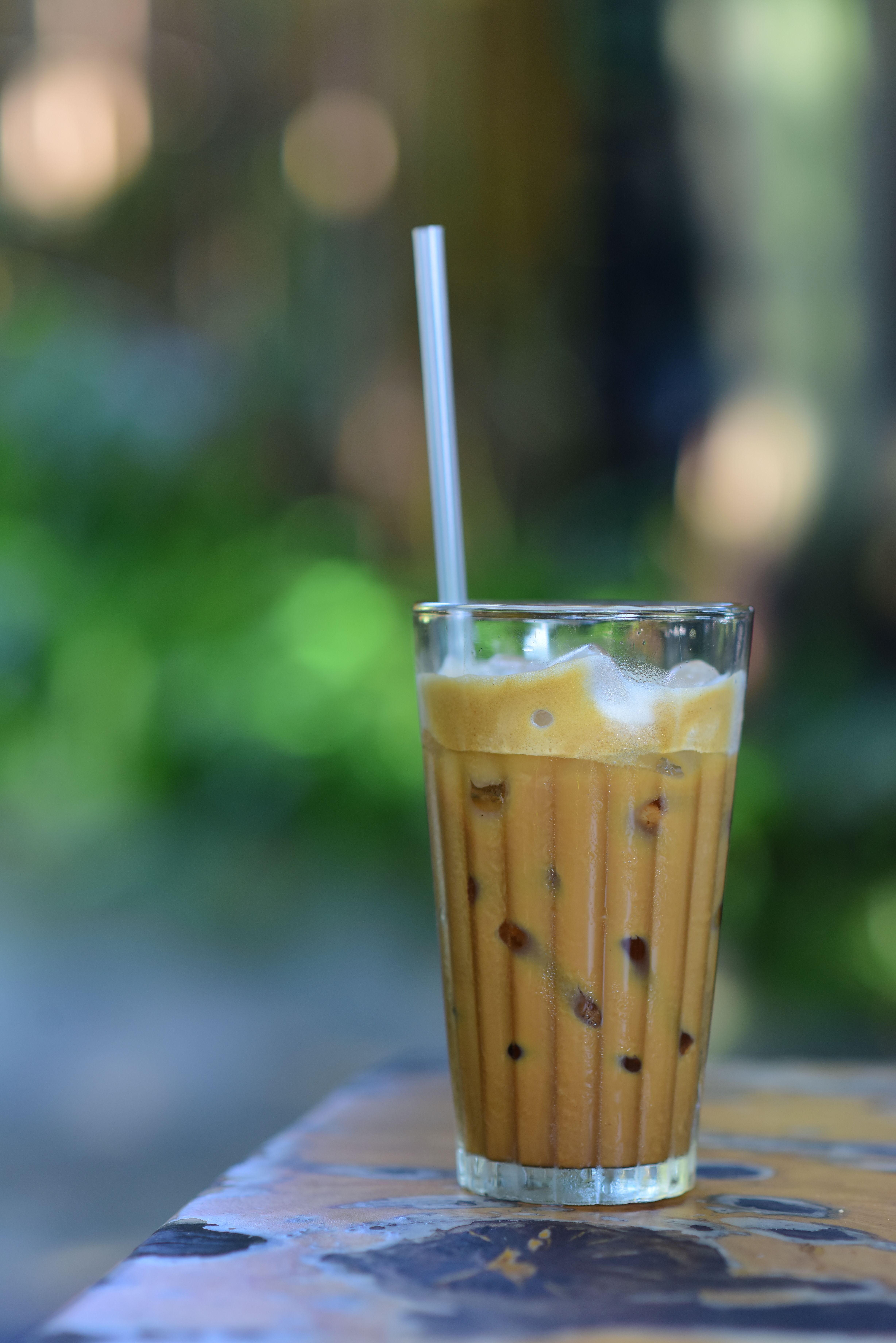 A refreshing glass of iced coffee with a straw, perfect for a summer day outdoors.