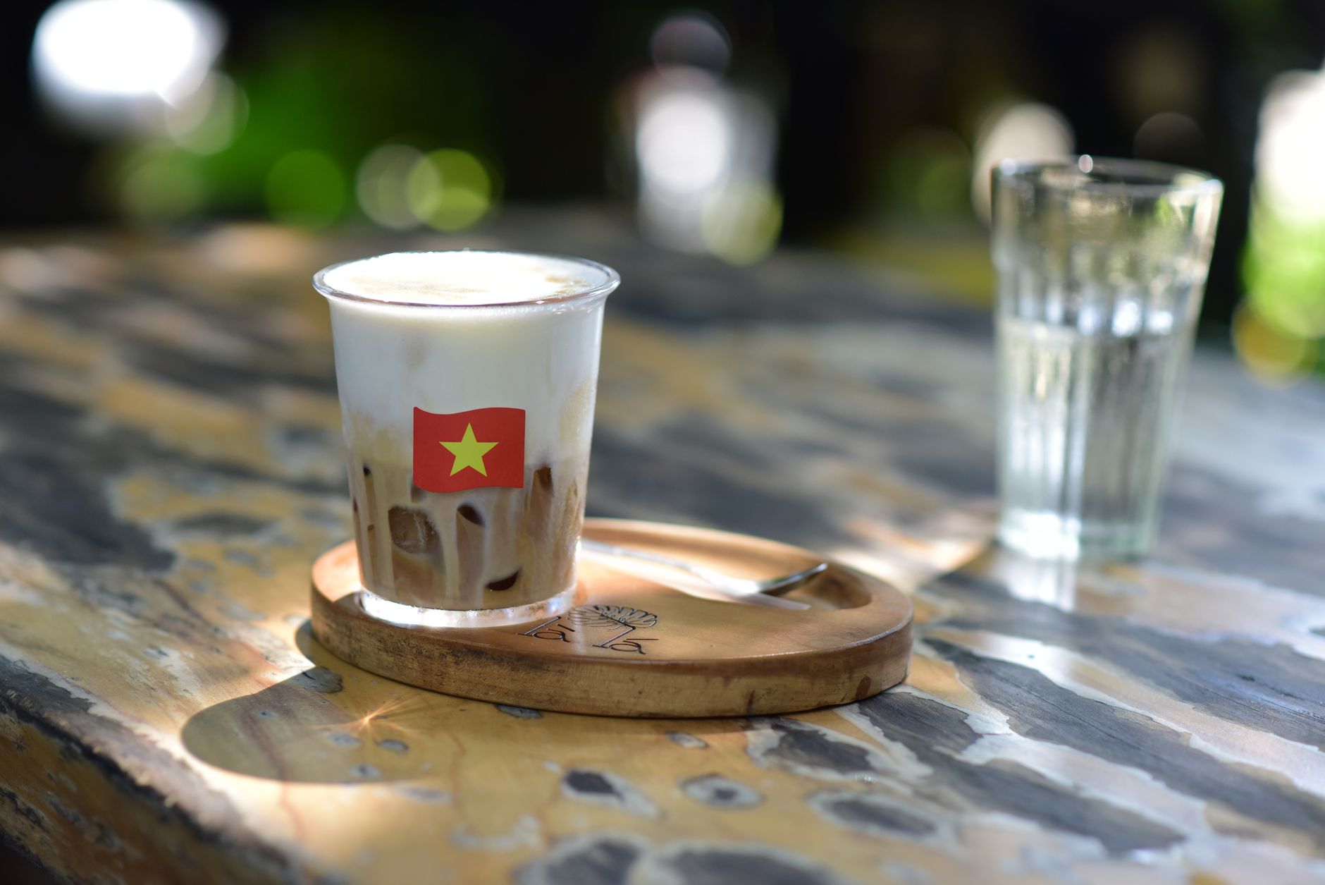 Refreshing iced coffee with milk, served on a rustic table outdoors, surrounded by natural light.