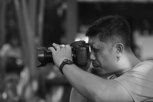 Free A dedicated photographer taking a picture outdoors, showcasing concentration and precision. Stock Photo