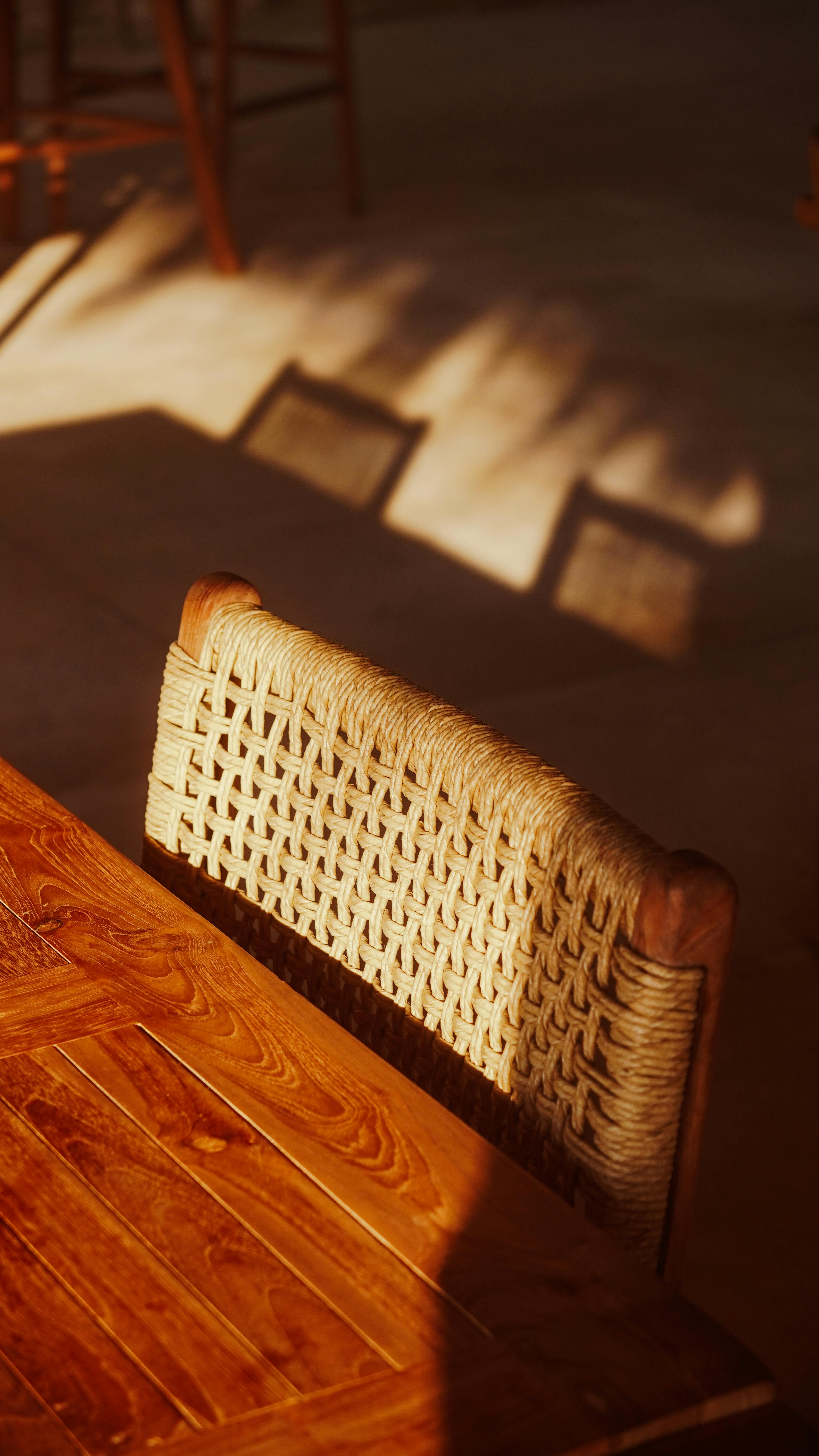 Gratuit La lumière du soleil projette des ombres chaleureuses sur une chaise et une table en bois. Un intérieur chaleureux et accueillant. Photos