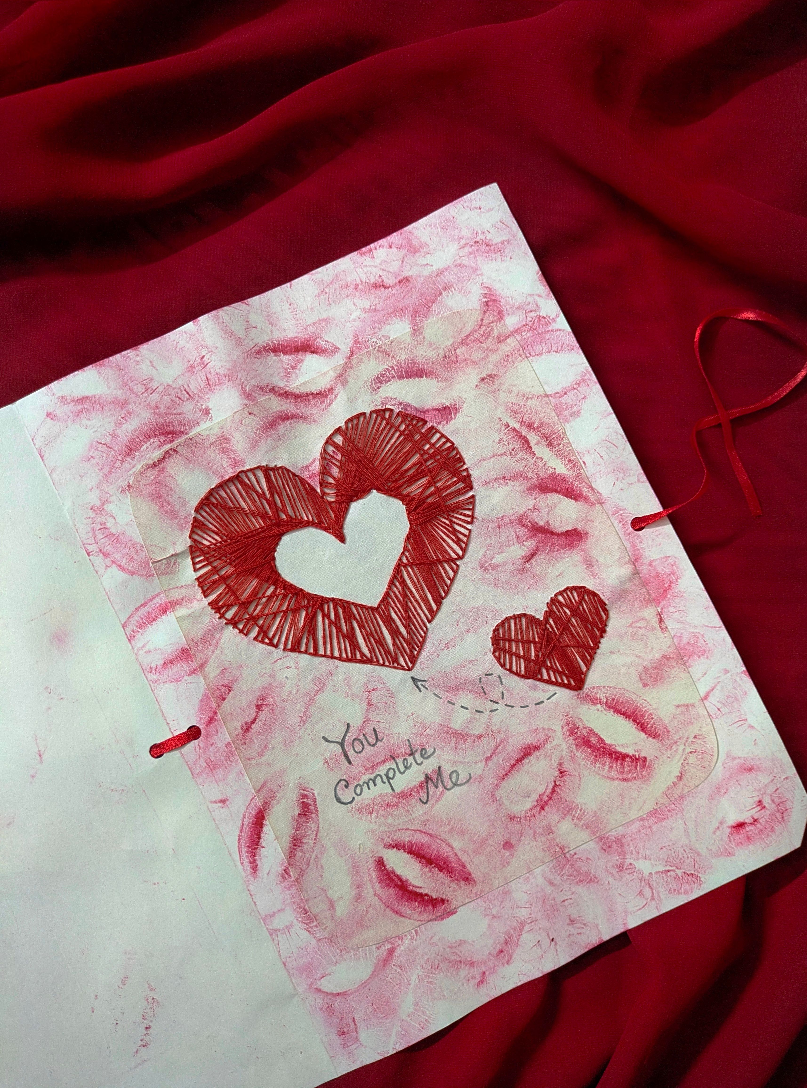 Artistic red heart drawing on textured paper with lip prints and romantic message.