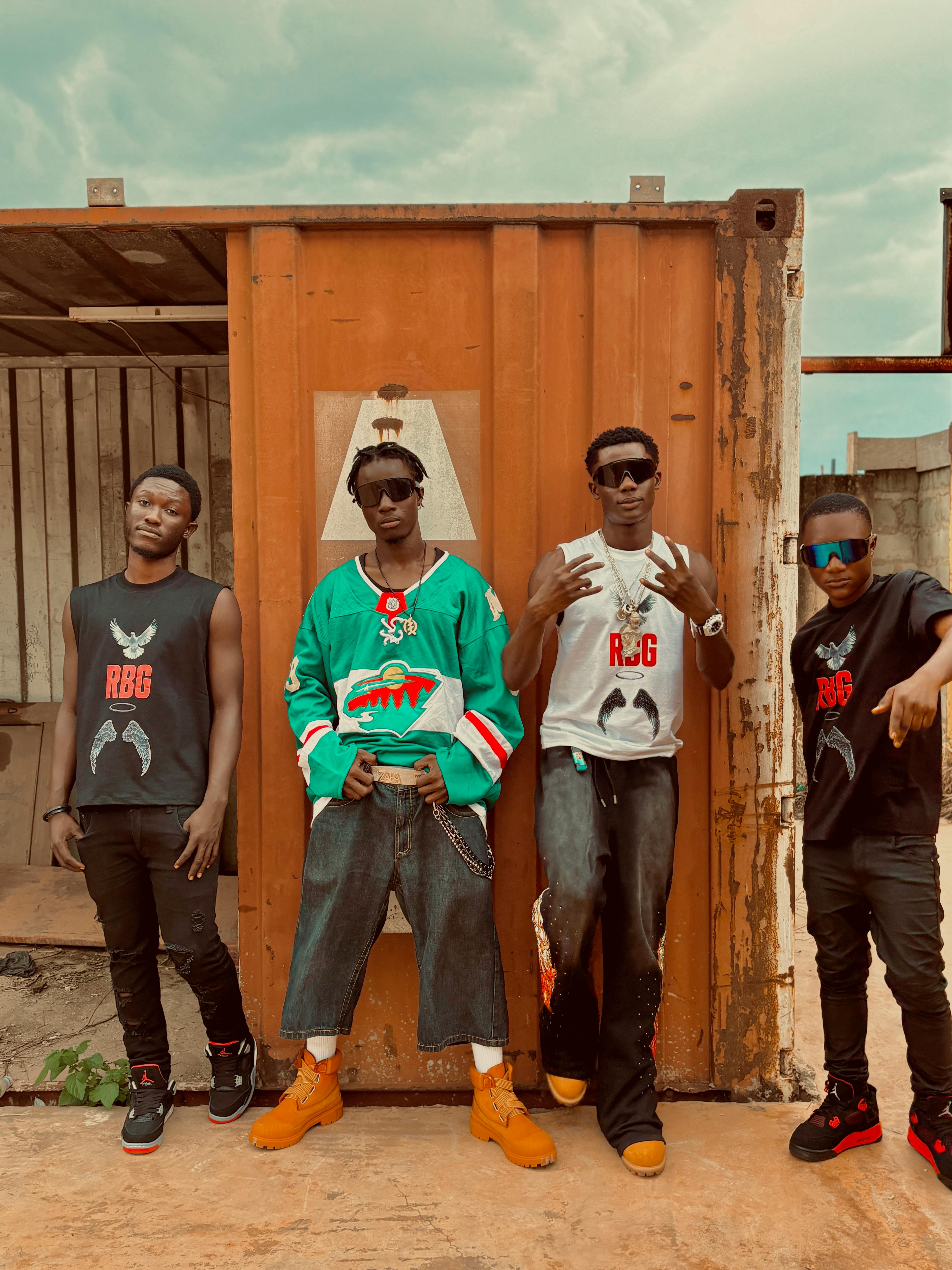 Four young adults posing in urban setting with street style fashion.