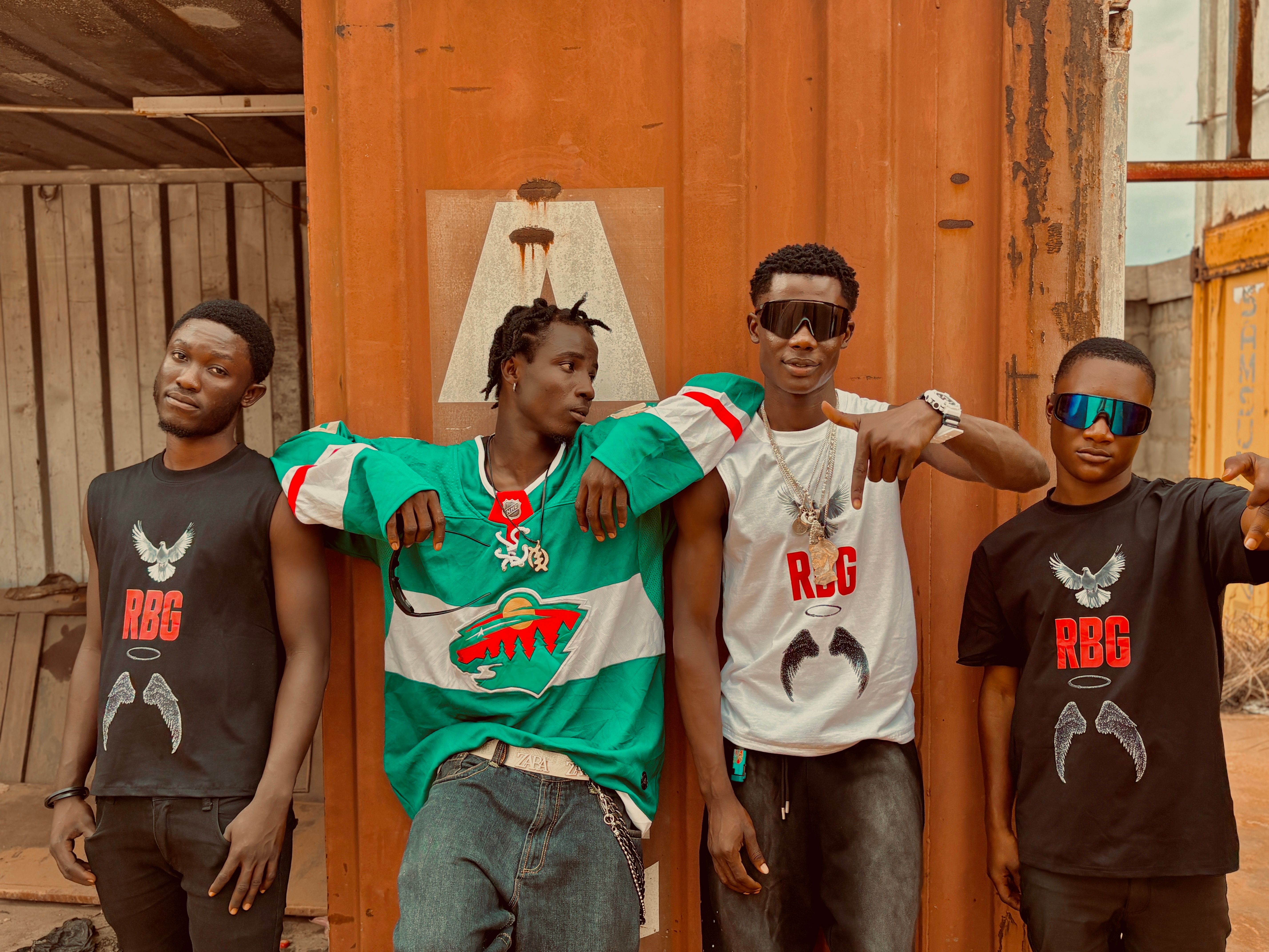 Four young adults showcase urban street style in a rustic setting.