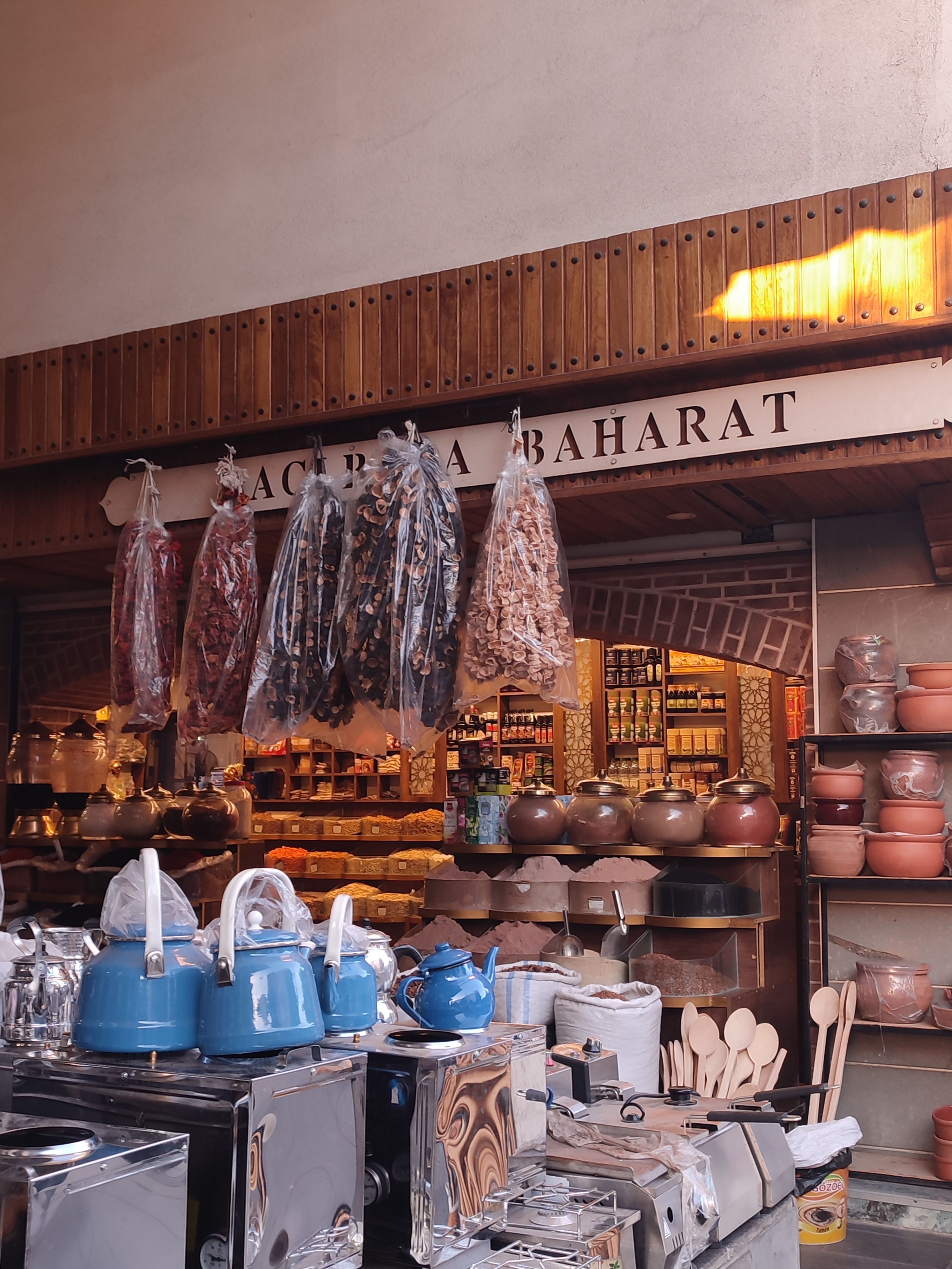 Rustic spice shop displaying teapots, cookware, and hanging herbs.