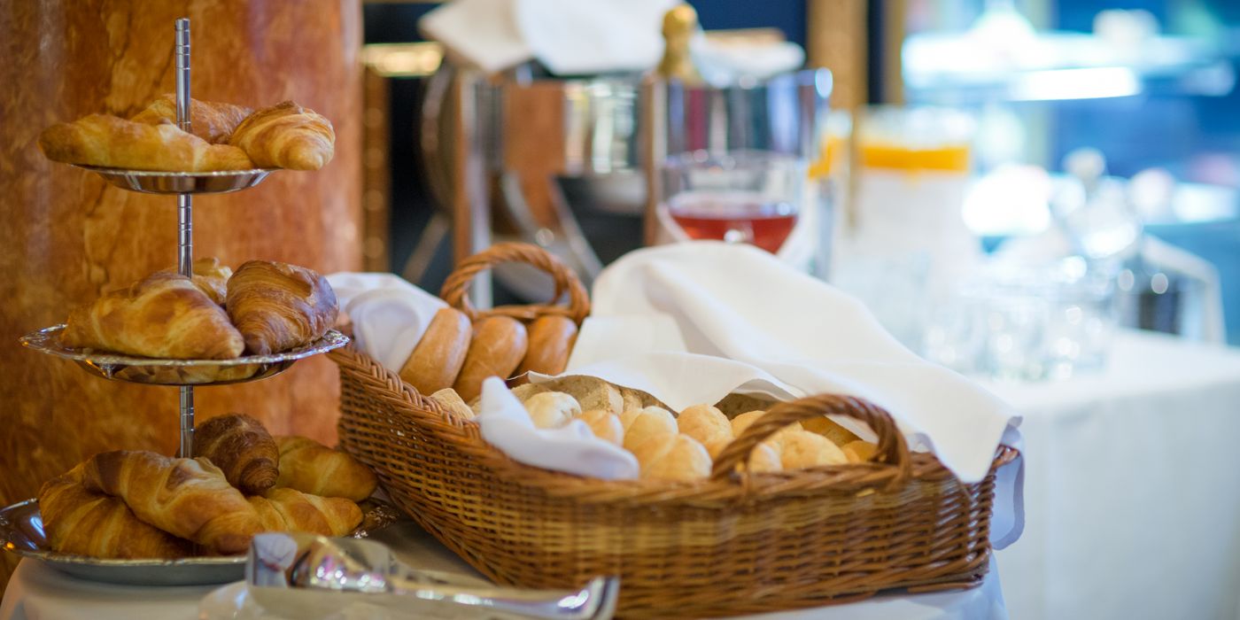 Hotel breakfast buffet with fresh croissants and bread on wooden boards