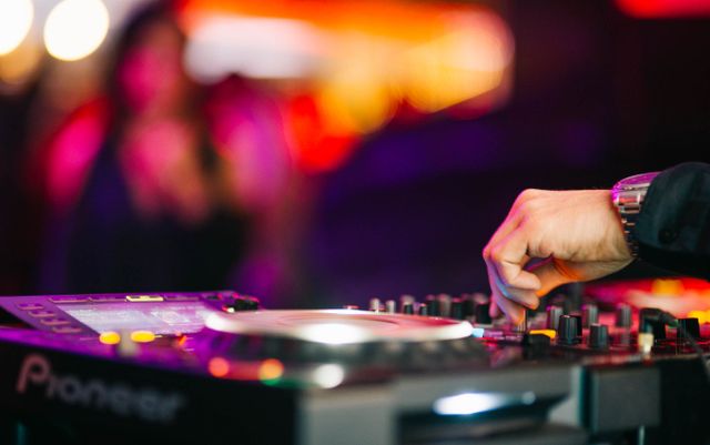 DJ qui mixe sur une table de mixage lors d'une soirée dans une salle animée