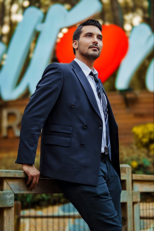 Free Stylish man in a suit posing outdoors with vibrant blurred signage backdrop. Stock Photo