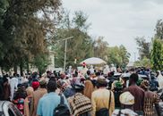 An outdoor cultural festival with a large crowd celebrating under colorful canopies and traditional garments.